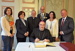 Beim Eintrag ins Gästebuch der Stadt Lippstadt schauten Nicole Heimlich, Referentin für Jugend und Familie beim Dekanat Lippstadt-Rüthen (l.), Dechant Thomas Wulf (3.v.l.), Bürgermeister Christof Sommer (3.v.r.) sowie seine Stellvertreter Franz Gausemeier (r.), Sabine Pfeffer (2.v.r.) und Helga de Horn (2.v.l.) Weihbischof Dominicus über die Schulter.  Foto: Stadt Lippstadt