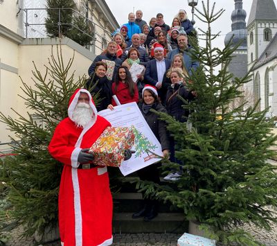 Die Weihnachtswunschbaumaktion startet: Ideengeberin Sabine Pfeffer (dritte Reihe von hinten, rechts), Bürgermeister Arne Moritz (Mitte), Helga Rolf (letzte Reihe hinten r.) und Christina Deimel-Fecke vom Fachdienst Jugend und Familie (vorne am Plakat) hoffen gemeinsam mit allen Beteiligten auf die Erfüllung der eingereichten Wünsche. Foto: Stadt Lippstadt