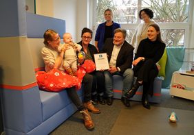 Ab sofort darf sich Lippstadt „Stillfreundliche Kommune“ nennen: Janine Schulte, Vorsitzende des Kreisverbands der Hebammen, überreichte die Urkunde an Bürgermeister Arne Moritz. Über die Auszeichnung freuen sich auch Iris Faulhaber, Fachbereichsleiterin Familie, Schule, Soziales (sitzend rechts), Verena Gimm-Burnic und Birgit Blumenröhr von der Mobilen Beratung (stehend)  sowie Iris Loick mit Sohn Jonte. Foto: Stadt Lippstadt