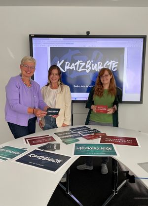„Kratzbürste“ oder „Meckerziege“: Inge Trame, Gleichstellungsbeauftragte Gütersloh, Daniela Franken, Gleichstellungsbeauftragte Lippstadt und Silke Williams, Gleichstellungsbeauftragte aus Minden präsentieren die Karten aus der Postkartenaktion. Foto: Stadt Lippstadt