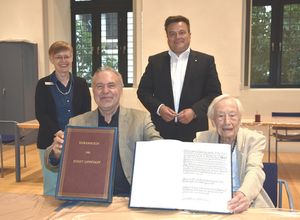 Dr. Walter Leimeier und Dr. Eva-Maria Dahlkötter (sitzend) präsentieren in Anwesenheit von Bürgermeister Arne Moritz und Stadtarchivarin Dr. Claudia Becker das Ehrenbuch der Stadt Lippstadt mit dem Eintrag für den ersten Ehrenbürger Lippstadts, Justizrat Georg Albert Schulenburg. Foto: Stadt Lippstadt