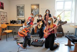 Guido Pyka, Musikschullehrer der Conrad-Hansen-Musikschule sowie die Ferienspaßteilnehmer des Kurses „E-Gitarre für Einsteiger“ Leo, Mara, Marie und David zeigten Organisatorin Elisa Stellmacher bei ihrem Besuch, wie man richtig rockt. Foto: Stadt Lippstadt