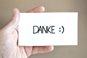 Hand hält Schuld mit "Danke" und Smiley