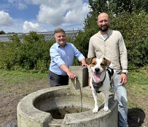 Der neue Schöpfbrunnen läuft: Hund Charly gefällt es und darüber freuen sich Bürgermeister Arne Moritz und Marvin Rölleke vom Fachdienst Grünflächen, Spielen und Sport. Foto:; Stadt Lippstadt
