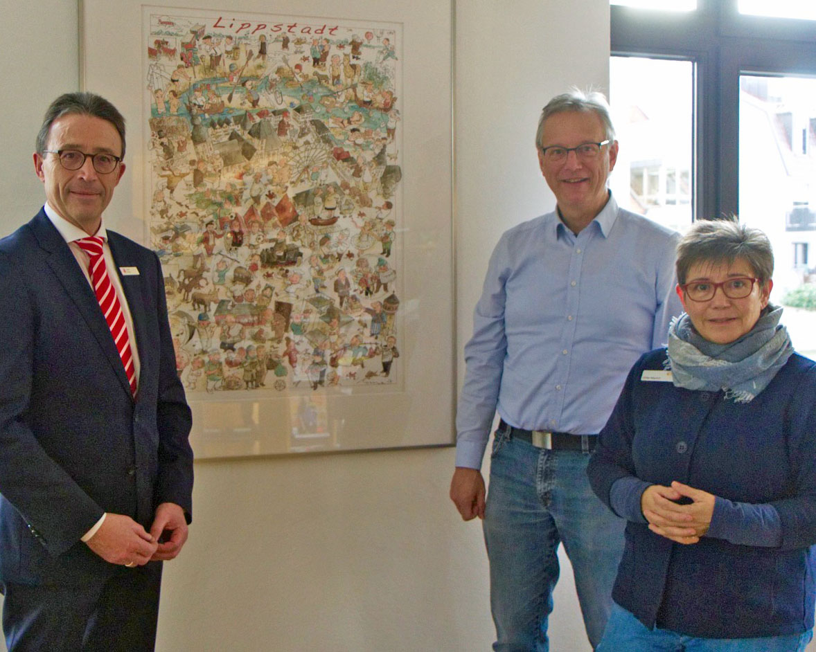Jürgen Riepe, Vorsitzender des Vorstandes der Sparkasse Lippstadt (l.), übergab das Original des Lippstädter „Wimmelbilds“ an Büchereileiterin Ulrike Weyrich und Wolfgang Streblow, Fachdienstleiter Kultur- und Weiterbildung. Foto: Stadt Lippstadt