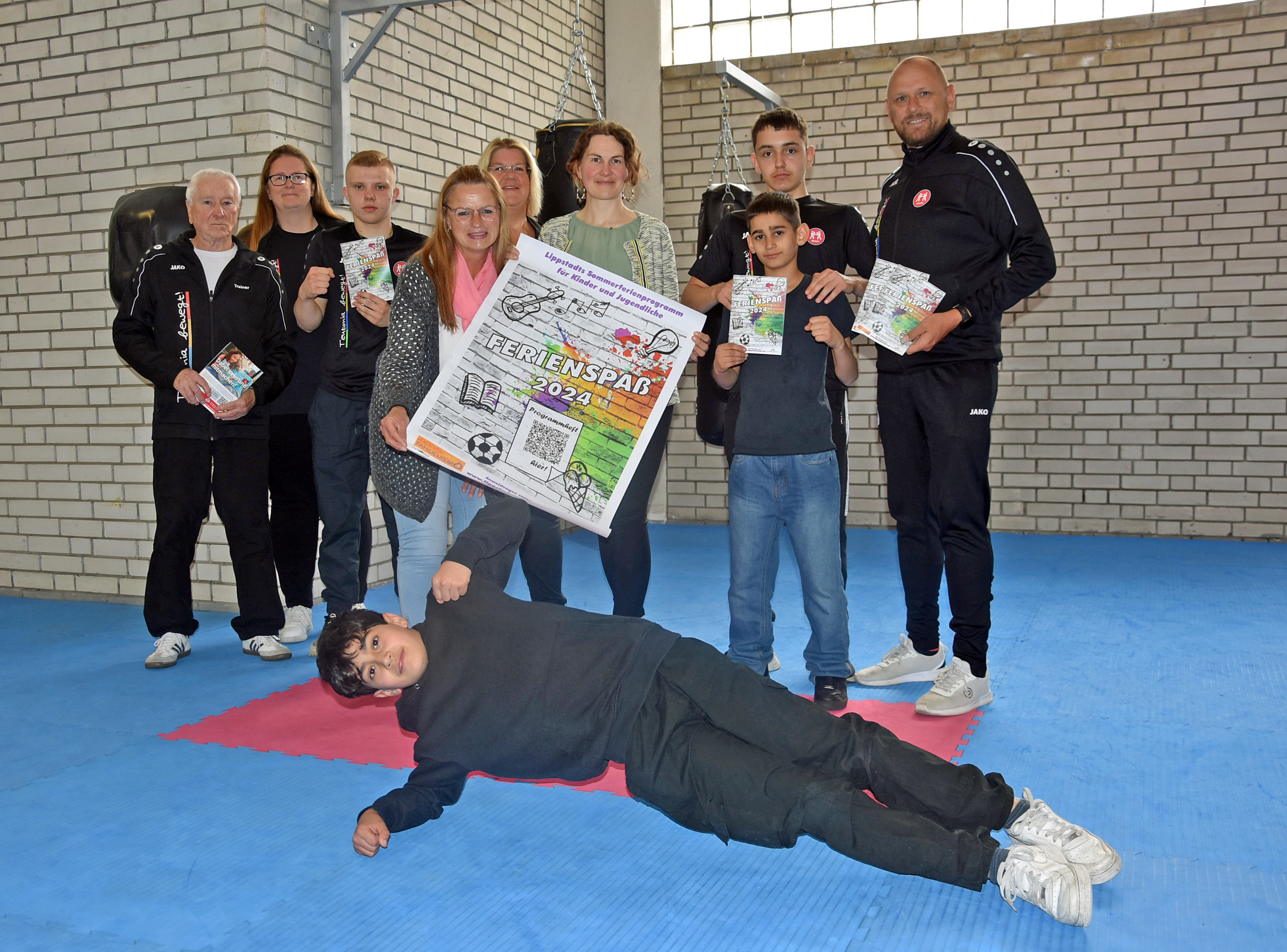 Die Sommerferien können kommen: Mit aktiven Sportlern der Abteilung Boxen des LS Teutonia 08 e.V. und Birgit Sommer von der Sparkasse Hellweg-Lippe (5.v.l.) stellten die Organisatoren um Elisa Stellmacher vom Jugend- und Familienbüro (4.v.r.) und Michaela Leiber-Mestekemper (4.v.l.) vom Stadtjugendring das Programm für den „Ferienspaß 2024“ vor.  Foto: Stadt Lippstadt
